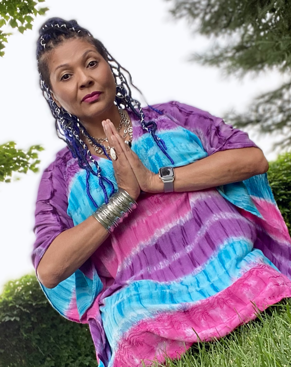 ModernWell member Dorothy Inez, Spiritual Practitioner, in a tie-die tshirt with hands in prayer and peaceful expression.